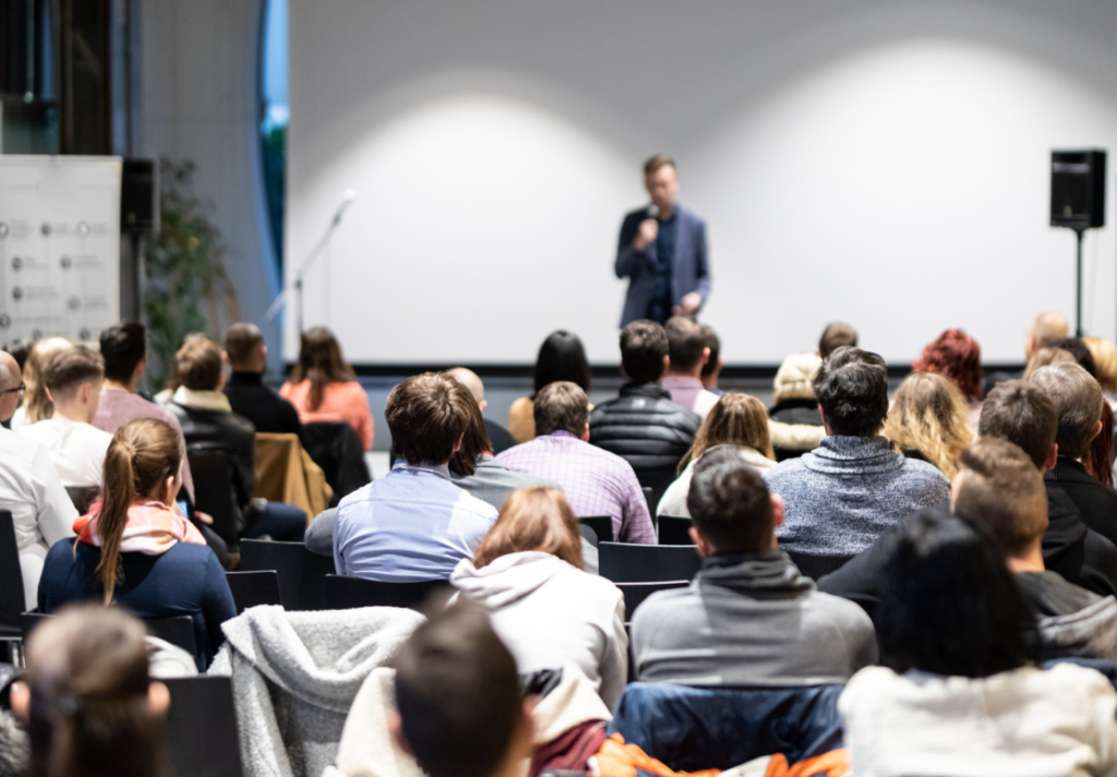 Startup founder pitching from the stage to the international audience during demoday.